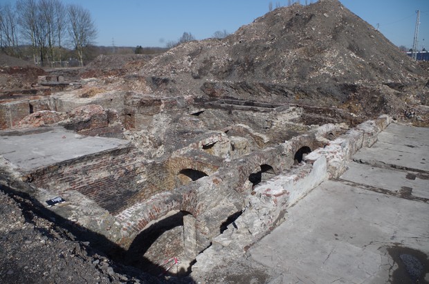 Blick auf eine Ausgrabung: Im Hintergrund ein Hügel Erdaushub, im Vordergrund freigelegte steinerne Strukturen (Foto: Archäologie am Hellweg eG). Blick auf eine Ausgrabung: Im Hintergrund ein Hügel Erdaushub, im Vordergrund freigelegte steinerne Strukturen (Foto: Archäologie am Hellweg eG).