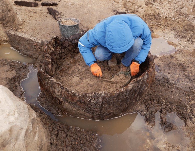 Jeder Eimer zählt: Bergung des lehmig-sandigen Sediments aus der Brunnenröhre. Aufgrund der dauerhaften Feuchterhaltung in diesem vom umgebenden Sand abweichenden Boden hoffen die Archäologen hier auf die Überreste von Pollen und anderen Pflanzenresten, um mehr über die Vegetation und Landschaft im Umfeld der Fundstelle zu erfahren (Foto: EggensteinExca/Sven Knippschild).