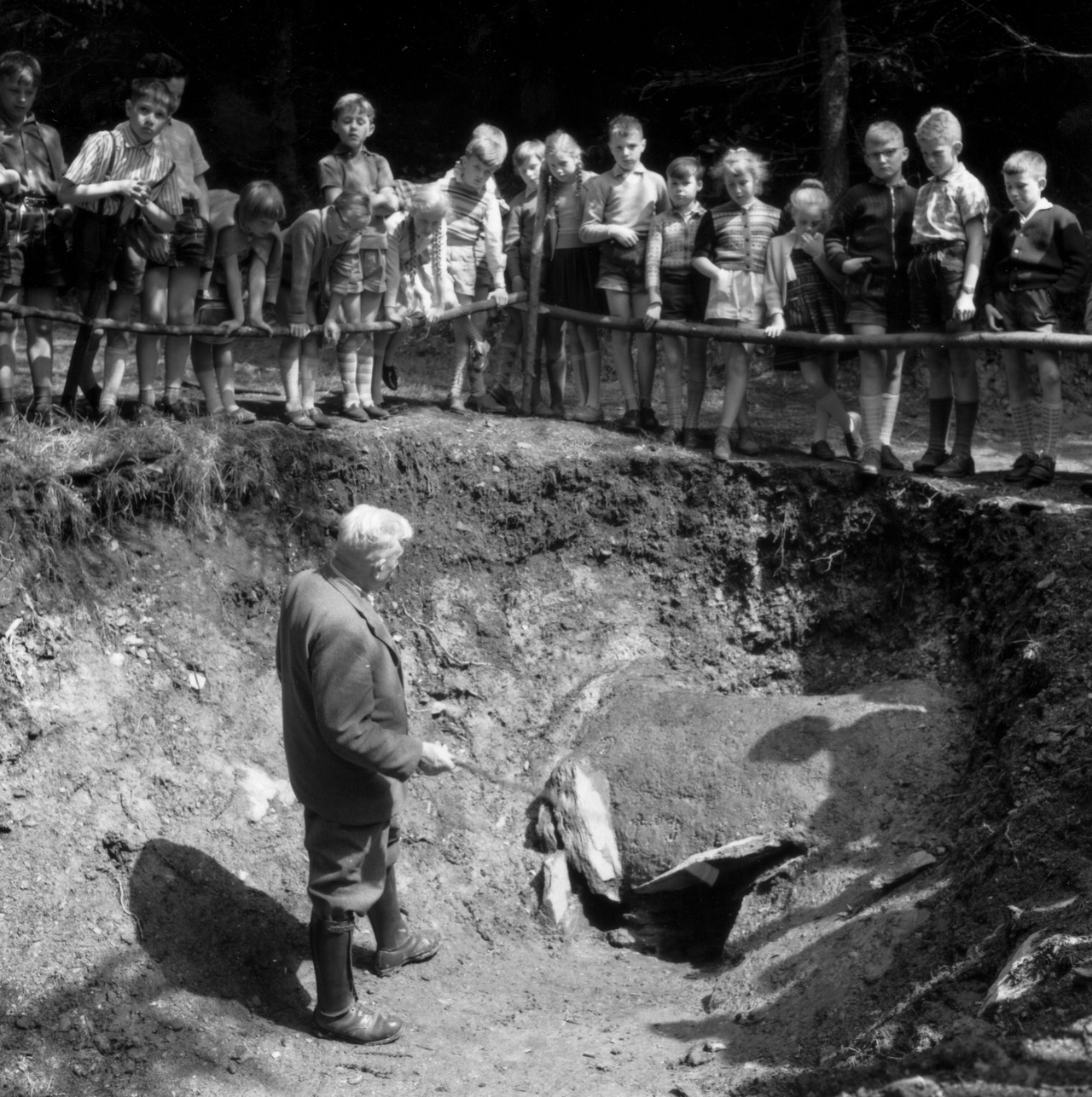 Otto Krasa erläutert im Engsbachtal einen ausgegrabenen eisenzeitlichen Verhüttungsöfen seinen nur teilweise aufmerksamen Schülern (Fotograf unbekannt).