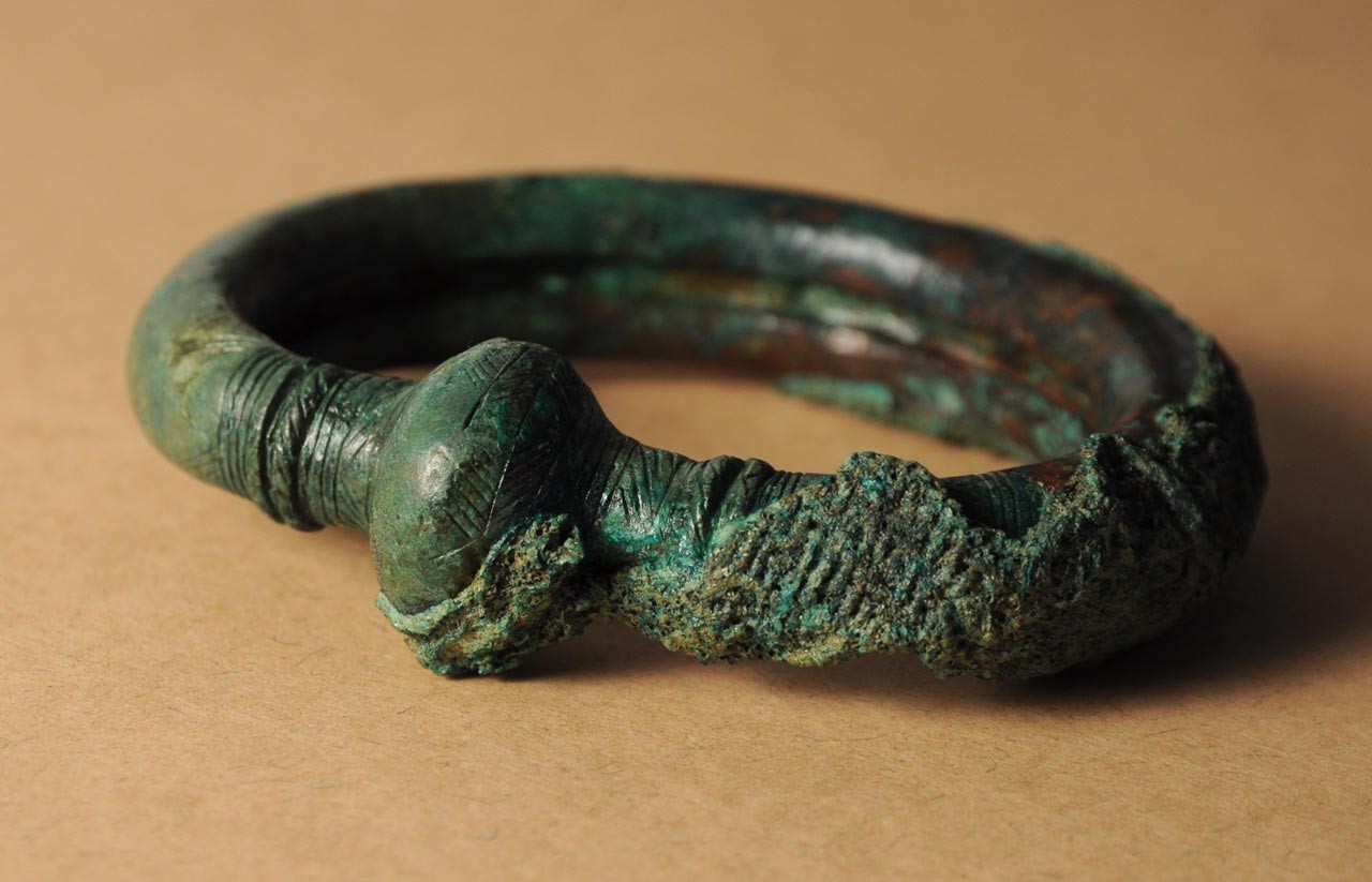Ein Fundstück, das sich z. Z. aus Dokumentationsgründen in der Außenstelle Bielefeld befindet: Bronzener Armring  mit Resten von Textilien; Foto: LWL/C. Hildebrand
