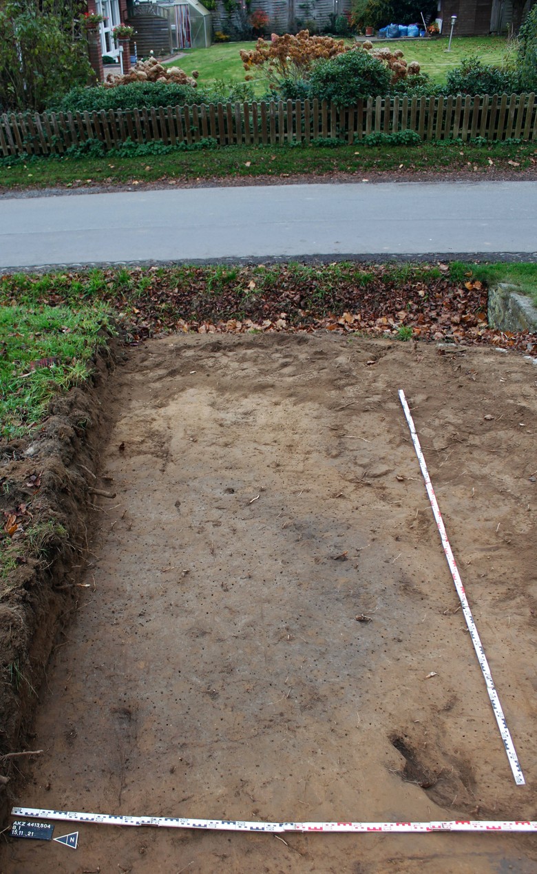 Im Baggerplanum der Zufahrt zeichnet sich die Grube als großer grauer Fleck relativ deutlich ab (Foto: LWL-AfW Olpe/M. Müller-Delvart).