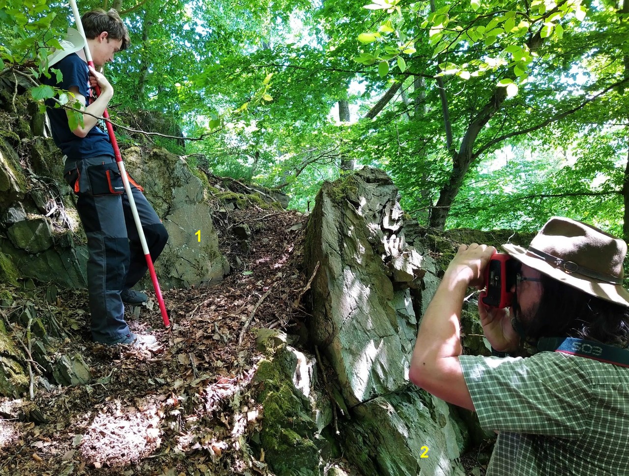 Lennestadt-Meggen, Nähe „Strumberg“. Fotografische Dokumentation des Hauptbildfeldes durch Manuel Zeiler; links im Bild unser aktueller FSJler Matthias Rosenthal. – 1 Hauptbildfeld; 2 die bekannte „DAUM“-Signatur. – Foto: LWL-AfW Olpe/M. Baales.