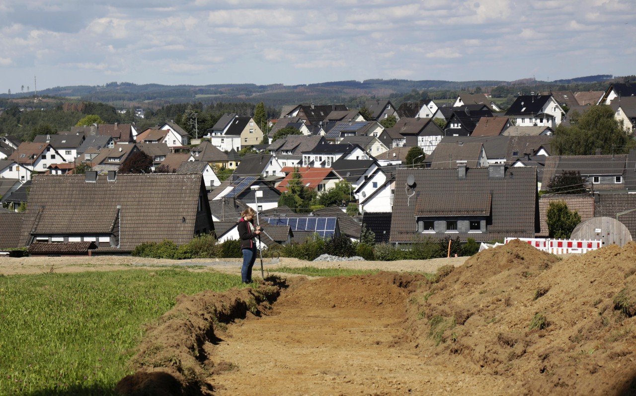 Wenden-Hünsborn (im Hintergrund), unterhalb einer vermeintlichen „Burgstelle“. Vermessung der Baggersondagen durch die FSJlerin Marleen Korte. – LWL-AfW/F. Geldsetzer.