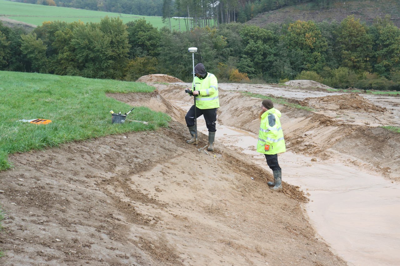 Der eisenzeitliche Pfosten befand sich in einer neuangelegten (durchnässten) Uferböschung. Dies erschwerte die Arbeiten, wie hier das Einmessen mit Hilfe des Differential GPS. – Foto: LWL-AfW Olpe/S. Sonntag
