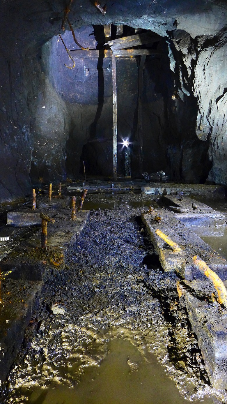 Blick in die Schachthalle der Grube Brüche mit Dampfmaschinenfundament im Vordergrund und Fördergerüst im Hintergrund