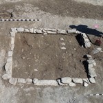 Von dem Kellerfundament des ehemaligen Gebäudes blieben nur wenige Steinlagen durch den fortwährenden Ackerbau erhalten. In der Mitte der vorderen Mauer befindet sich der Schwellstein, über den der Keller ehemals betreten wurde (Foto: LWL-AfW Olpe / M. Zeiler). (vergrößerte Bildansicht wird geöffnet)